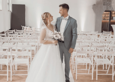 Brautpaar nach der Trauung vor weißer Bestuhlung im hellen Innenraum der Alten Lehrwerkstatt Solingen