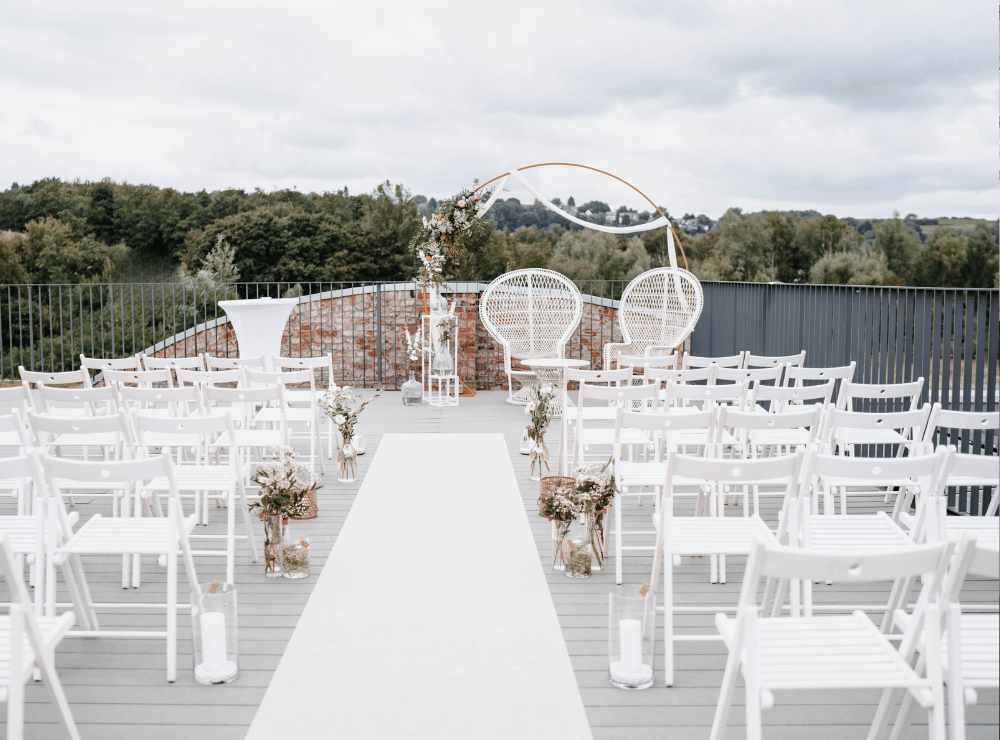 Freie Trauung auf der Dachterrasse der Alten Lehrwerkstatt Solingen mit weißer Bestuhlung, Traubogen und Blick ins Grüne